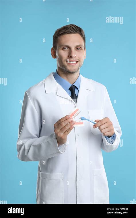 Dentist With Jaws Model And Toothbrush On Light Blue Background Oral