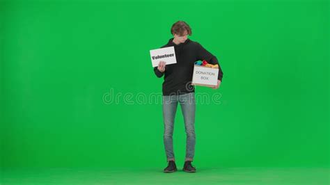 A Man Holds A Poster Labeled Volunteer And A Box Labeled Donation Box