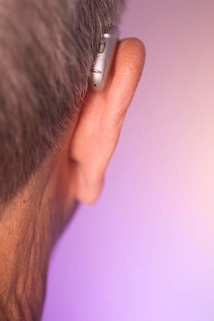 Premium Photo Close Up Of Man Wearing Hearing Aid Against Wall