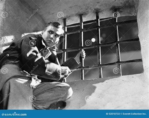 Low Angle View Of A Young Man Trying To Escape From A Prison Cell Stock