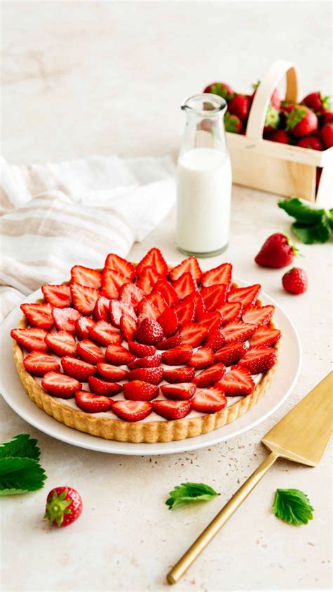 A Strawberry Tart On A White Plate Next To Some Strawberries