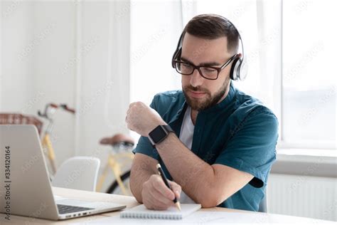 Concentrated Millennial Man In Glasses And Wireless Headphones Make