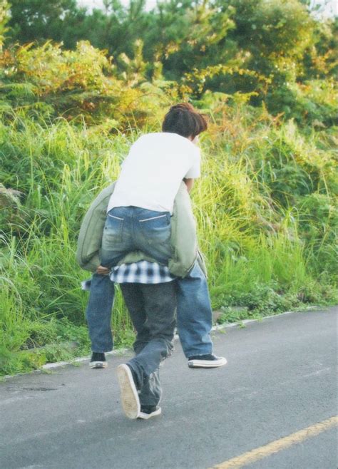 A Man Is Walking Down The Street With His Back Turned To The Camera