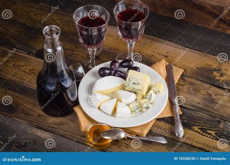 Placa De Queso Con La Uva Y El Vino En La Madera Foto De Archivo