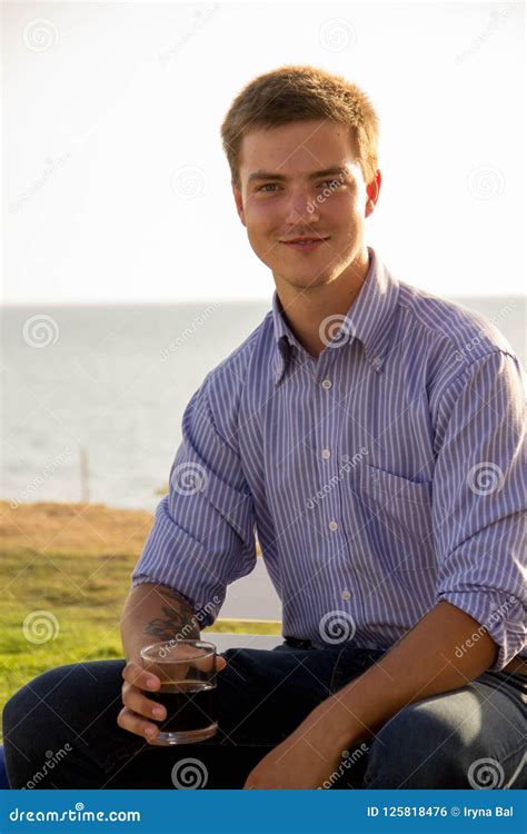 Hombre Atractivo Y Feliz Joven Que Sienta Y Que Sostiene Un Vidrio Con