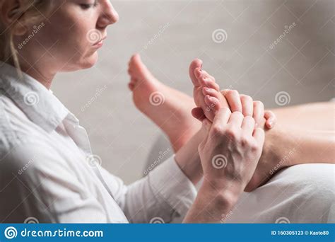 Professional Female Masseur Giving Reflexology Massage To Woman Foot