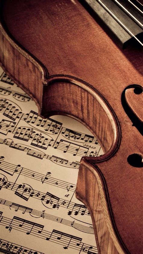 An Old Violin Sitting On Top Of Sheet Music