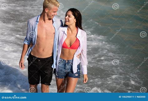 Happy Cheerful Couple Having Fun On A Tropical Beach At Sunset Stock