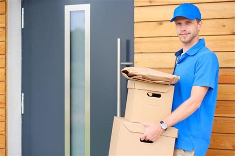 Repartidor Sonriente En Uniforme Azul Que Entrega La Caja Del Paquete