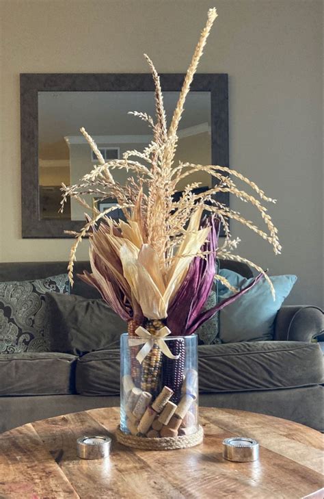 A Vase Filled With Dried Flowers Sitting On Top Of A Table Next To A Couch