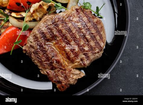 Meat Steak With Grilled Vegetables On A Black Plate Zucchini Onion