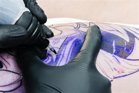 Premium Photo Professional Tattoo Artist Makes A Tattoo On The Male Leg