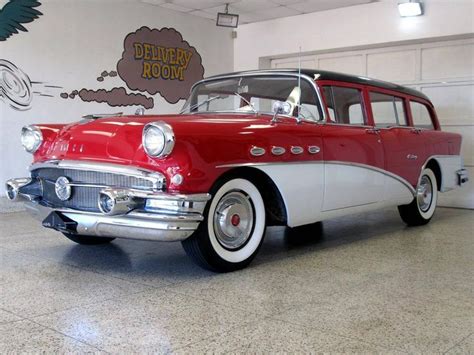 An Old Red And White Car Is Parked In A Garage With A Sign On The Wall