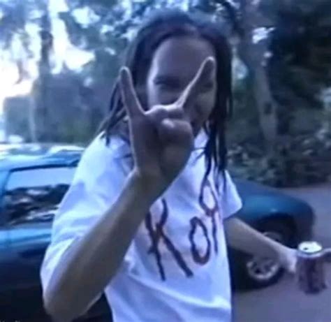 A Man With Dreadlocks Making The Peace Sign While Standing In Front Of