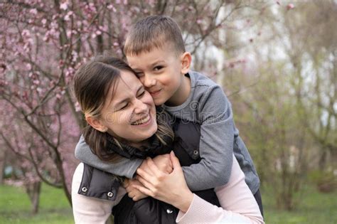 Happy Mom And Son Hugging Among Cherry Blossoms In Spring Stock Image