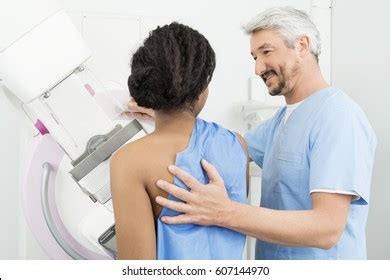 Mature Doctor Assisting Patient Undergoing Mammogram Stock Photo