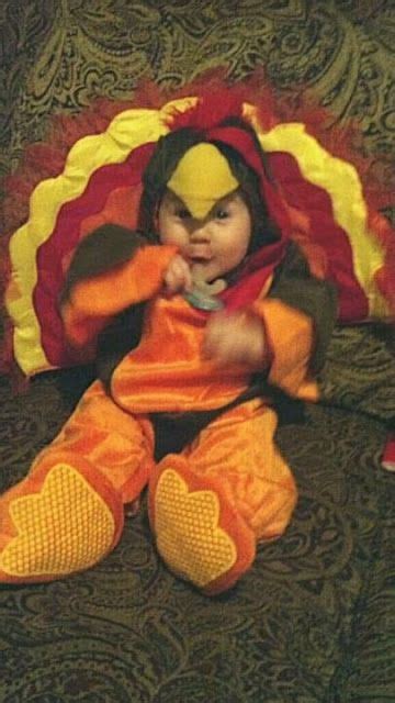 a baby dressed as a turkey sitting on top of a couch