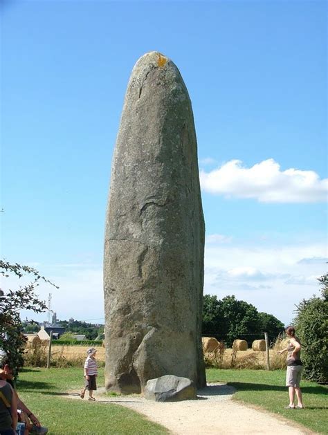 People Are Sitting On The Grass Near A Large Rock