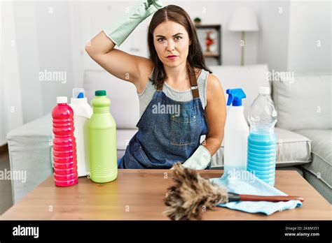 Young Brunette Woman Wearing Cleaner Apron And Gloves Cleaning At Home Confuse And Wonder About