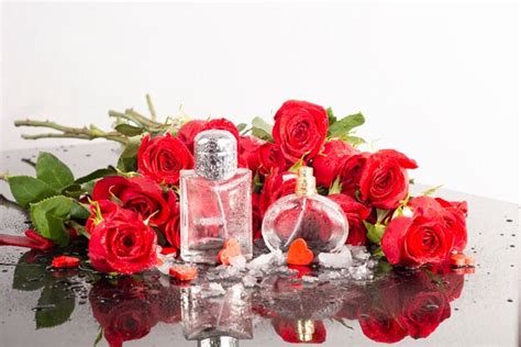 Premium Photo Bottles Of Perfumes Against The Background Of A Bouquet Of Red Roses In Drops Of