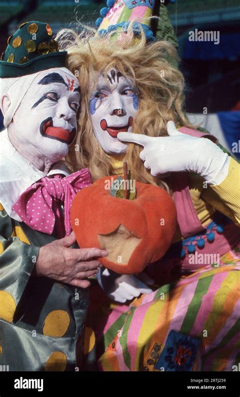 Close Up Photo Of 2 Ringling Brothers Clowns In Full Makeup Holding A Pumpkin That Seems To Have