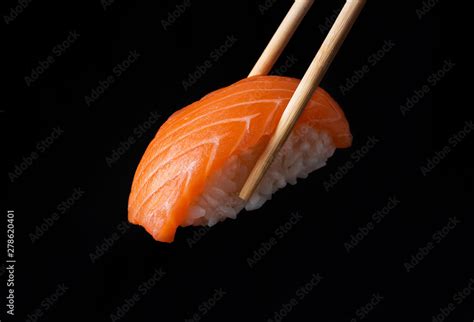 Traditional Japanese Nigiri Sushi With Salmon Placed Between Chopsticks