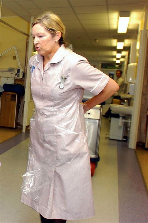 Nhs Healthcare Assistant Putting Her Plastic Apron On Nurse Dress