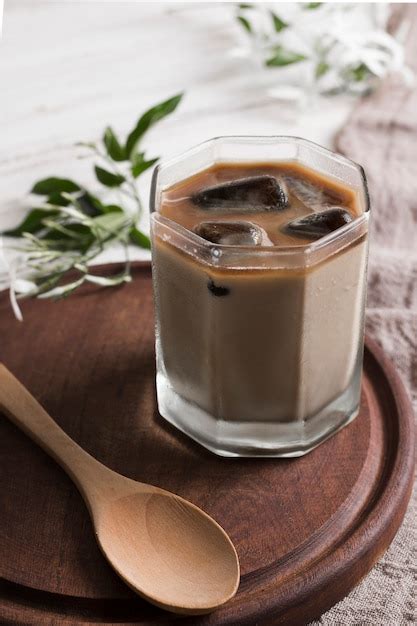 Kaffee mit Eiswürfeln in Glas und Holzlöffel Kostenlose Foto