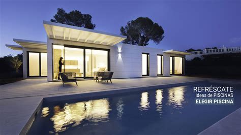 A House That Has A Pool In Front Of It And Is Lit Up At Night