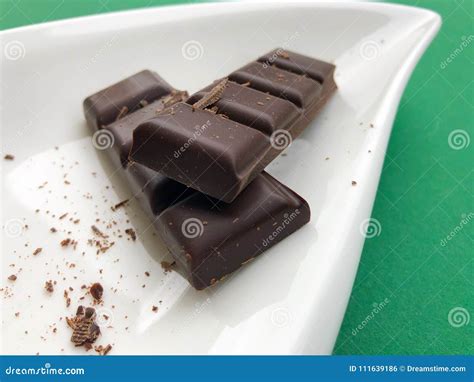 Dark Chocolate On A White Plate Isolated On Green Background Stock