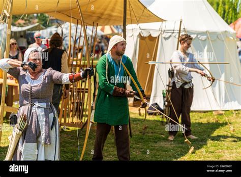 Medieval reenactment with a woman in period costume, firing a bow and ...