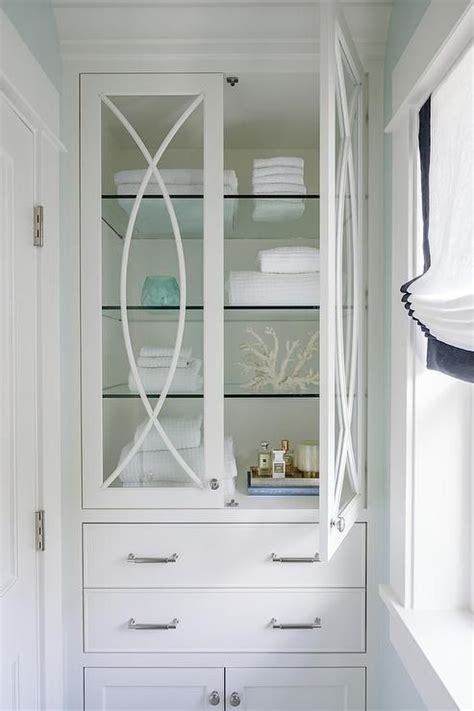 A Glass Mullion Linen Cabinet Fitted With Glass Shelves Is Built In