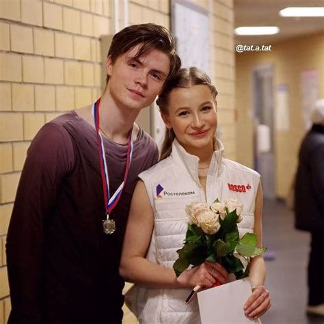 A Man And Woman Standing Next To Each Other In Front Of A Brick Wall