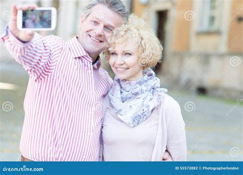 Happy Middle Aged Couple Taking Selfie Through Smart Phone In City