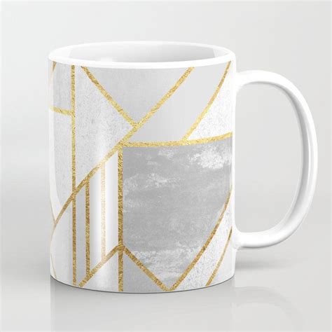 A White And Gold Coffee Mug With Geometric Design On The Front In An