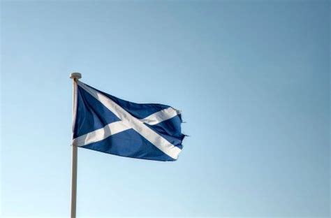 the scottish flag is flying high in the sky