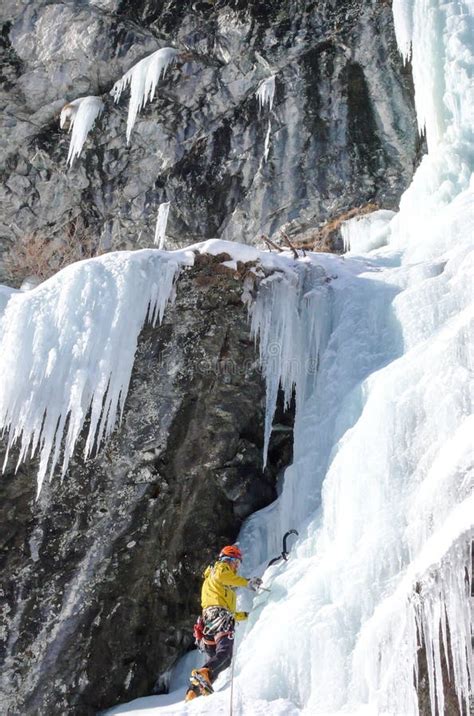 Male Mountain Guide Climbing A Steep Frozen Waterfall On A Cold Winter