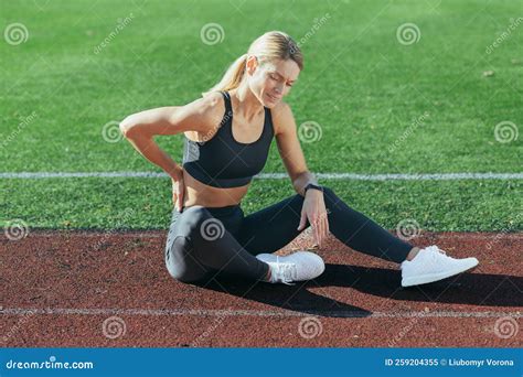 Injured Female Athlete Sits On The Stadium Treadmill Has Severe Back Pain Holds Her Hand By