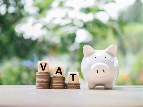 Piggy Bank And Wooden Blocks With The Word Vat On Stack Of Coins The