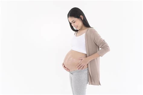 Beautiful pregnant woman applying moisturizing, stretch mark cream on