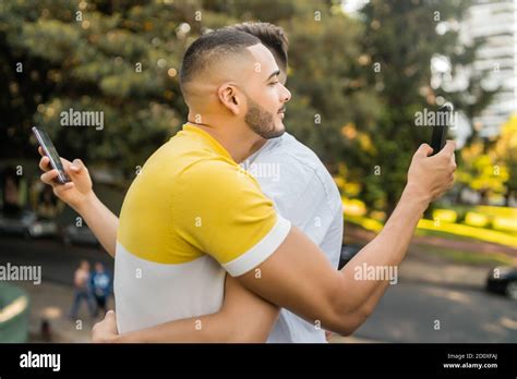 Portrait d un jeune couple gay qui s embrasse en utilisant son smartphone Couple problème et