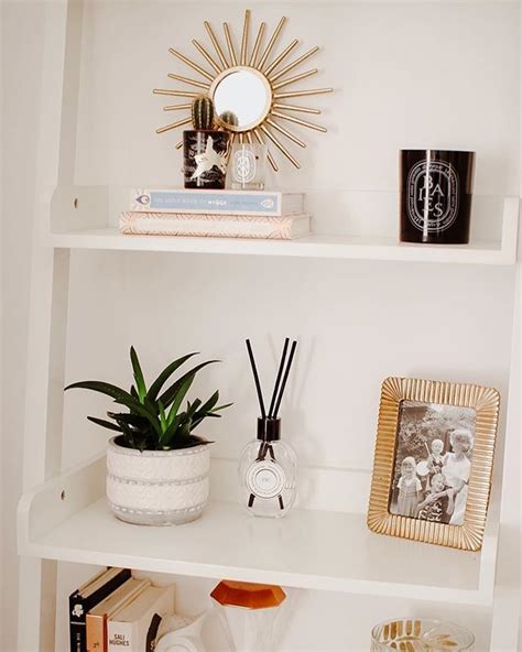 A White Shelf Filled With Books And Other Items Next To A Mirror On Top