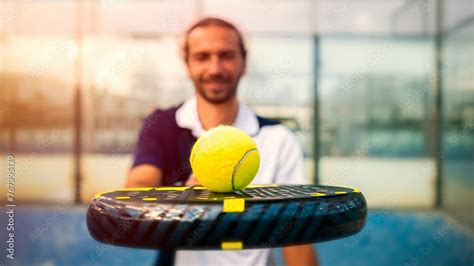 Monitor Of Padel Holding Black Racket With Yellow Tennis Ball Over