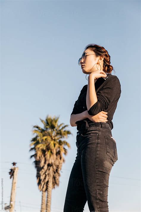 Young Female Wearing Black Clothes Standing Outdoors By Palm Tree By Stocksy Contributor