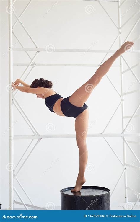 Graceful Gymnast Stands On A High Black Barrel Makes Complex Shapes