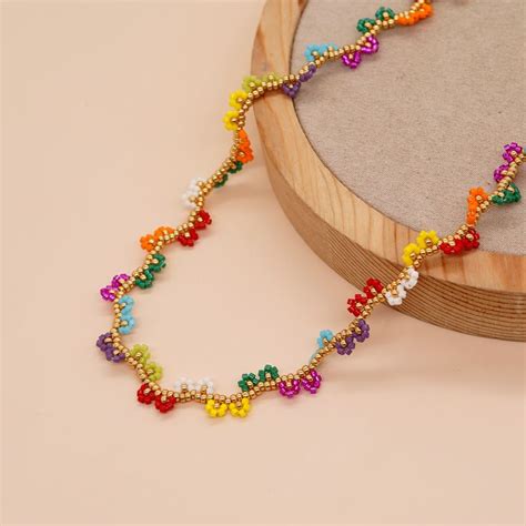 A Multicolored Beaded Necklace Sitting On Top Of A Wooden Stand Next To