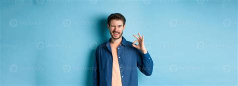 Positive smiling guy winking and showing okay sign, praising good work