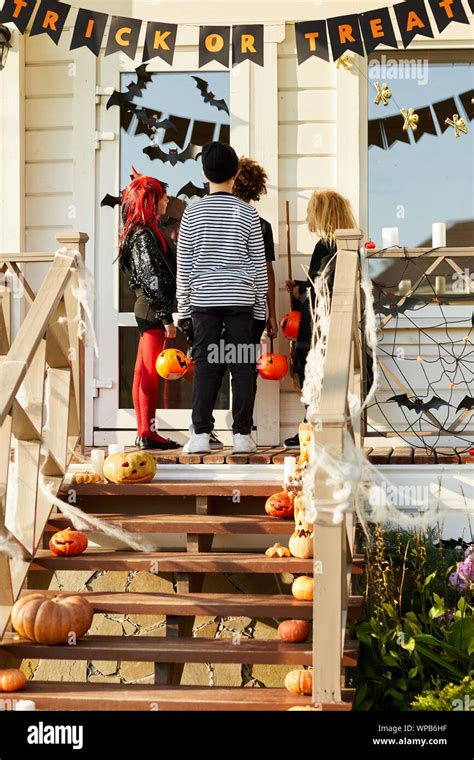 Back View Of Children Trick Or Treating On Halloween Kids Standing On