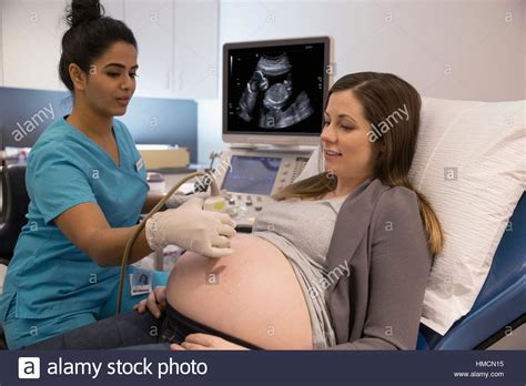 Female Nurse Performing Ultrasound On Pregnant Woman In Examination