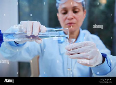 Details Graduated Cylinder In The Hands Of A Blurred Scientist Pouring